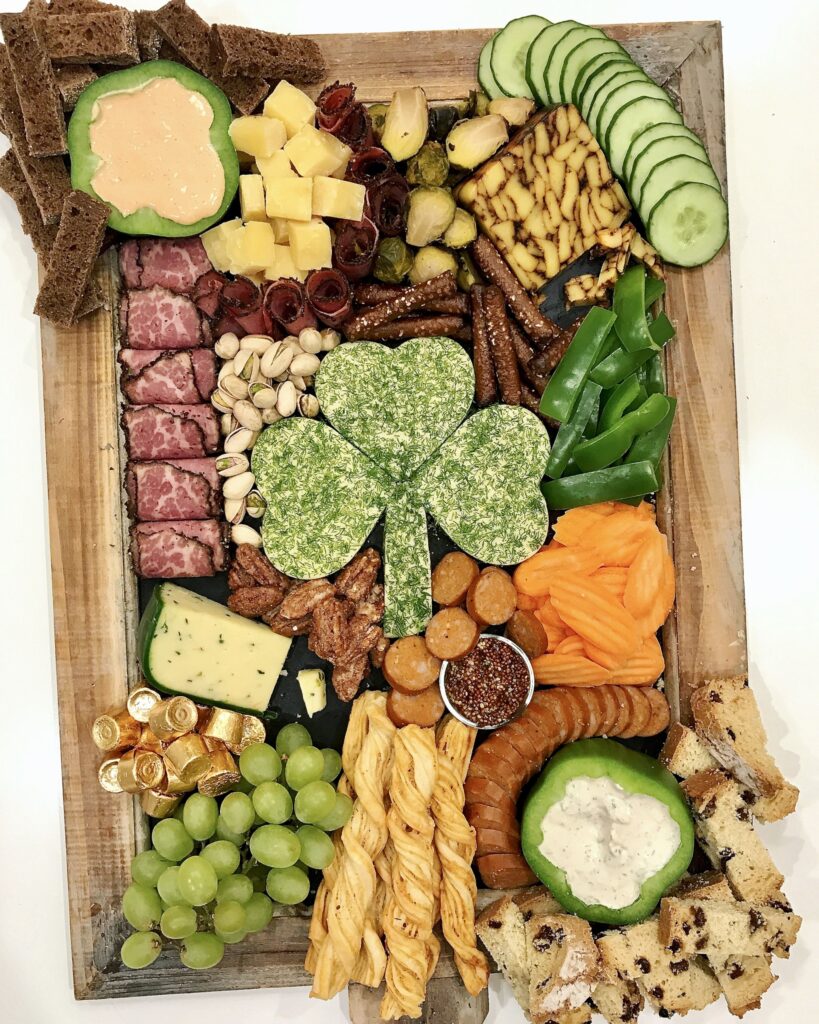 St. Patrick's Day Charcuterie Board with cheese in the shape of a shamrock, corned beef, carrot chips, breads, chocolates
