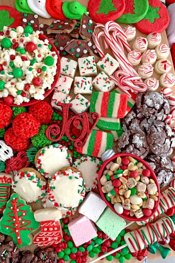 Christmas dessert board covered in cookies and red and white candies, popcorn and candy canes