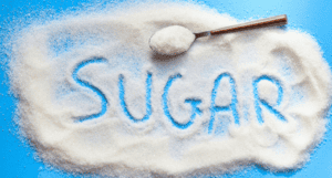 sugar spilled on a blue counter with the word sugar spelled out
