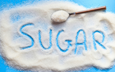 sugar spilled on a blue counter with the word sugar spelled out